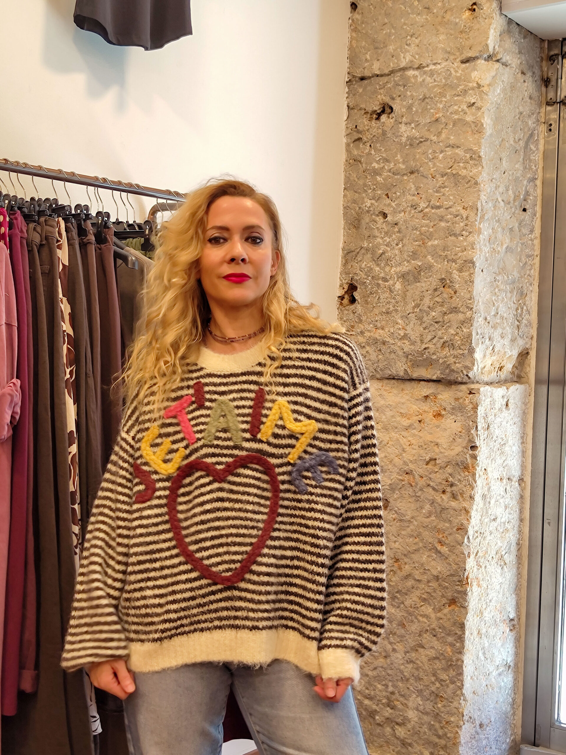 Mujer con jersey oversize de rayas en color chocolate con corazón central y letras de colores “J’taime”, vista frontal.