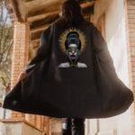 Mujer de espaldas con abrigo gris antracita oversize e ilustración artística en la parte trasera.