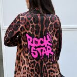 Mujer de espaldas con blazer de leopardo efecto neopreno y mensaje “ROCK STAR” en fucsia.
