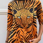 Mujer con camiseta “Sueños” asimétrica de media manga en tejido satinado elástico con estampado de leopardo, vista frontal.